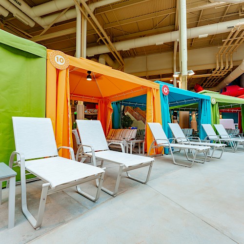 The image shows colorful cabanas and lounge chairs in a water park setting with multiple water slides in the background.