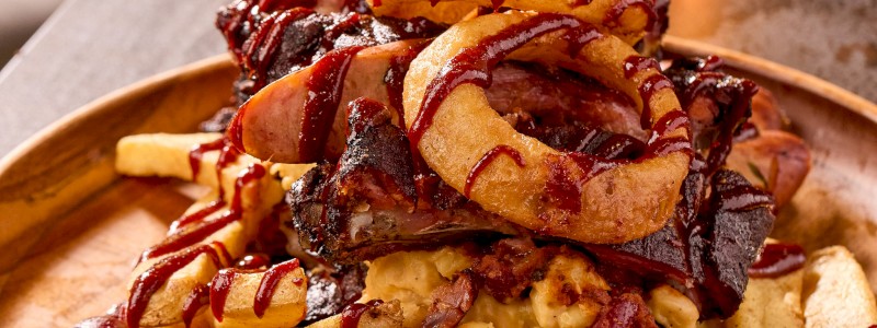 Smoked Pork Rib Rack Smackdown - Steak fries, Smokehouse Mac, smoked ham beans, sausage links, onion rings, and house BBQ sauce