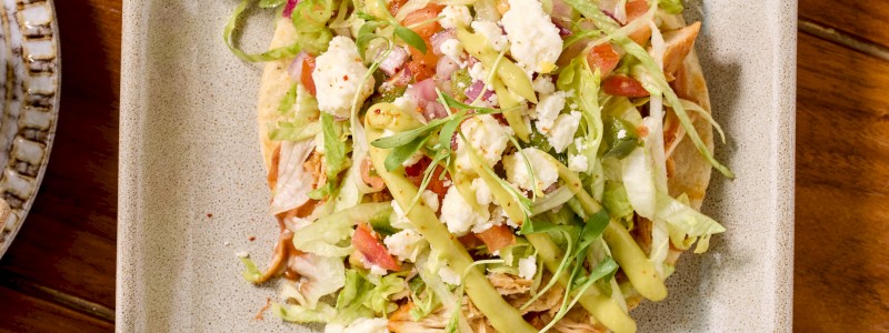 Sopes Traditional - Shredded chicken, thick corn tortilla, pinto & chorizo beans,
shaved lettuce, and pico de gallo