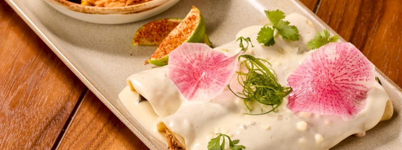 Poblano Braised Chicken Enchiladas - Shredded chicken, poblano peppers, and queso blanco, served
with pinto beans and Mexican rice