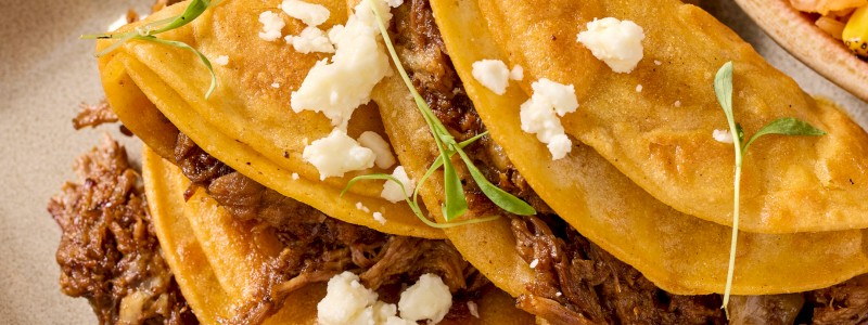 Birria Tacos - Ancho chile-braised beef,
cilantro, diced onions,
tomatoes, and queso fresco