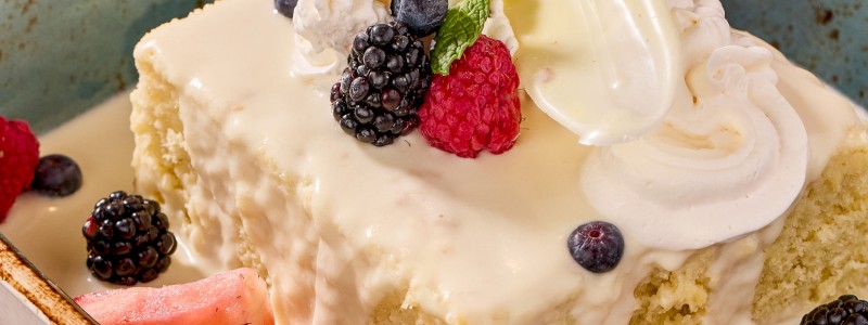 Tres Leches Cake - Traditional three-milk cake topped with whipped cream and seasonal berries