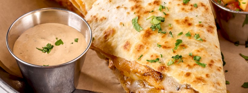 CHICKEN QUESADILLA - Chicken tinga, shredded pepper jack, and Cheddar.
Served with fresh peach salsa and sriracha crema.