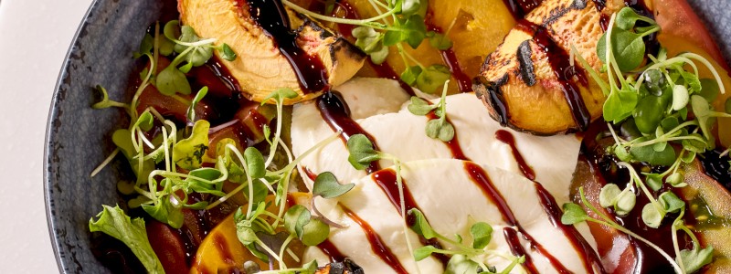 PEACH CAPRESE SALAD - Heirloom tomatoes, heritage blend, fresh grilled
peaches, Thai basil, burrata, and balsamic reduction.